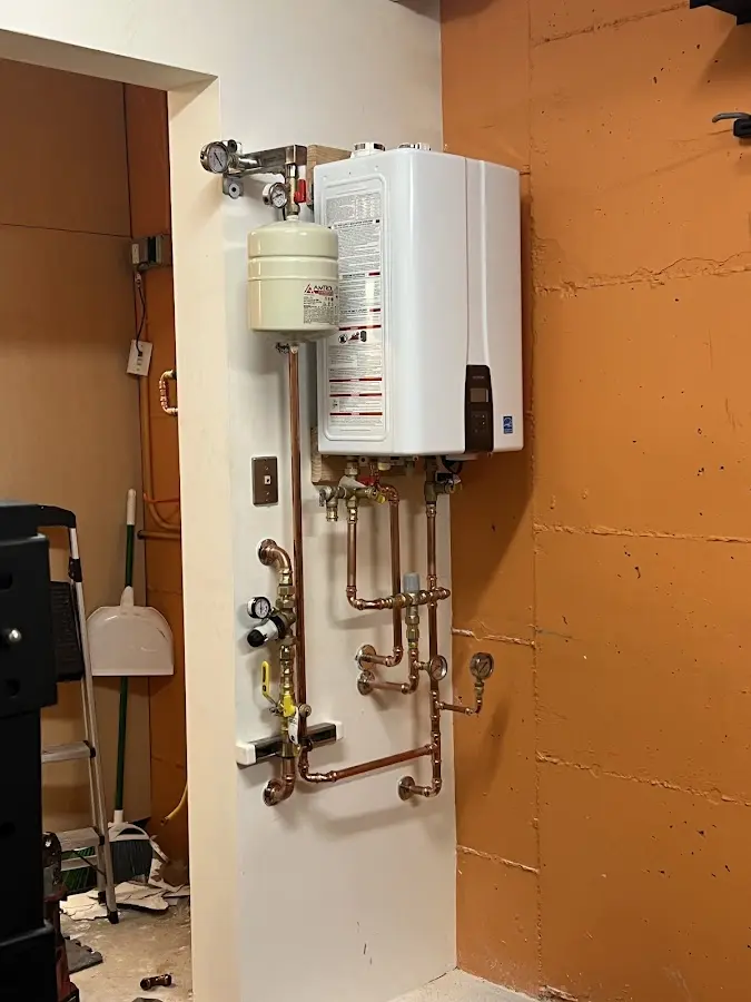 Plumbing technician inspecting water heater connections in Burke